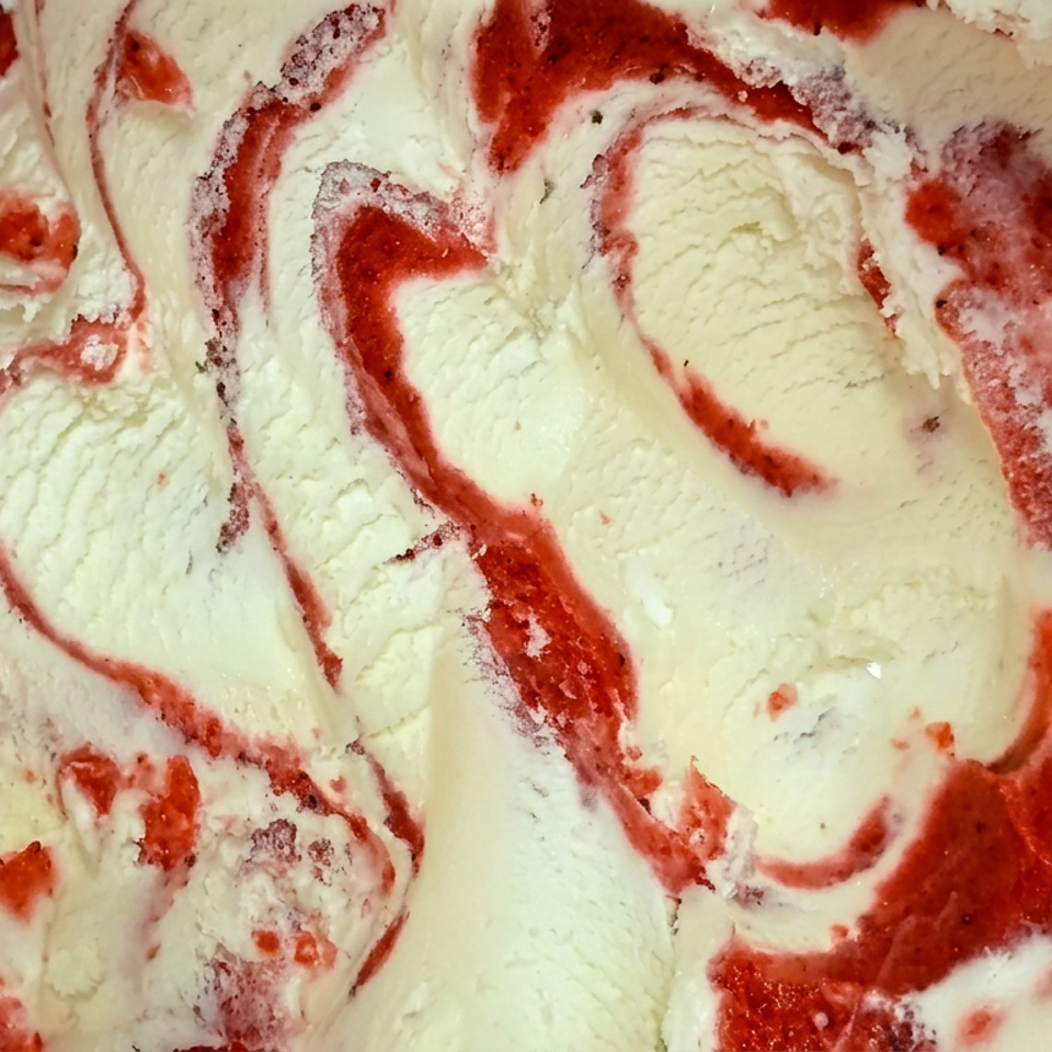 Close-up of creamy vanilla ice cream swirled with bright red strawberry sauce.